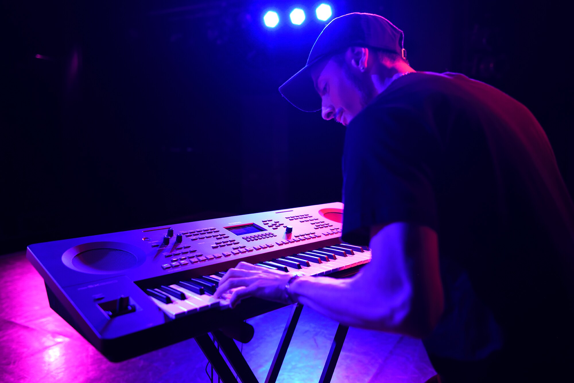 En person som spiller på et Yamaha Arranger Workstation på et stativ under scenelys