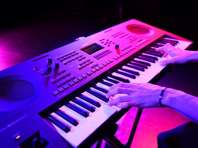 Nærbilde av hender som spiller på et keyboard under en livefremføring.