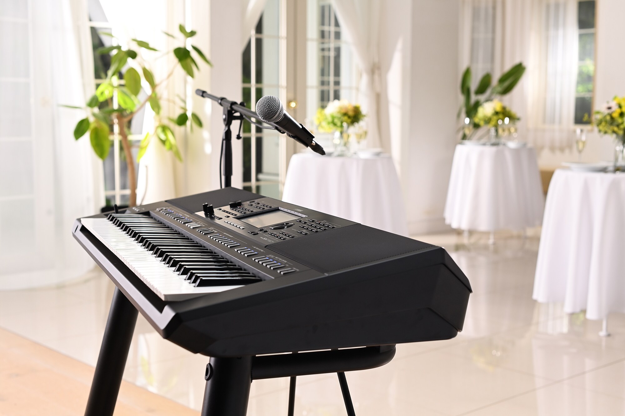Yamaha Arranger Workstation PSR-SX720+ med mikrofonstativ i et festlokale