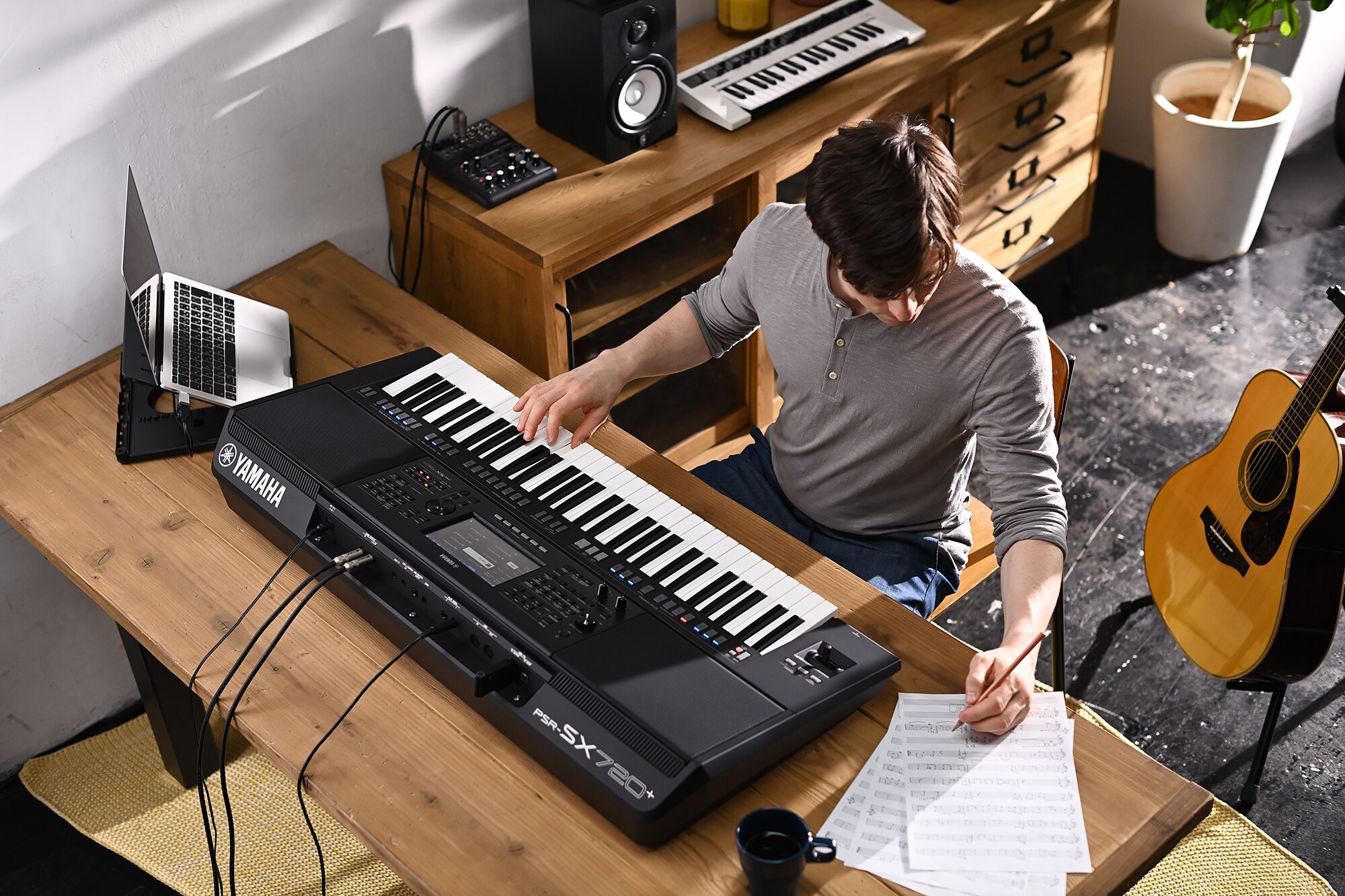 Bilde av en person som skriver på noter mens vedkommende spiller på Yamaha Arranger Workstation PSR-SX720+