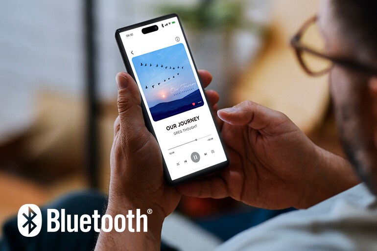 Bluetooth-logoen og en mann som bruker en smarttelefon til musikkavspilling.