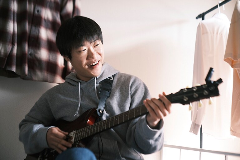 En mann som prøver å spille gitar for første gang
