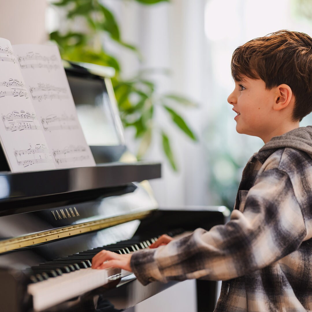 Et barn spiller med glede på det opprettstående pianoet i B-serien