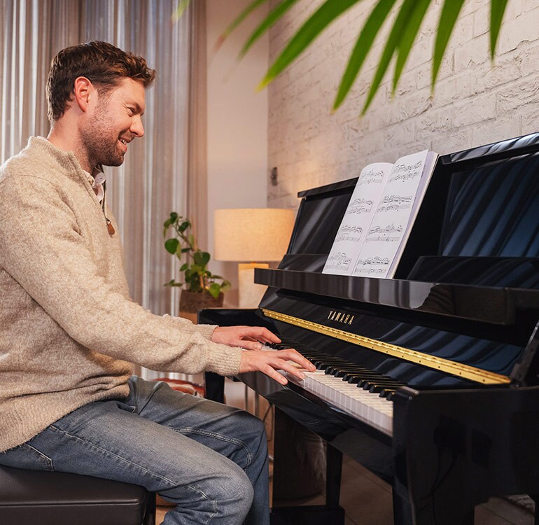 En kvinne spiller med glede på det opprettstående pianoet i B-serien