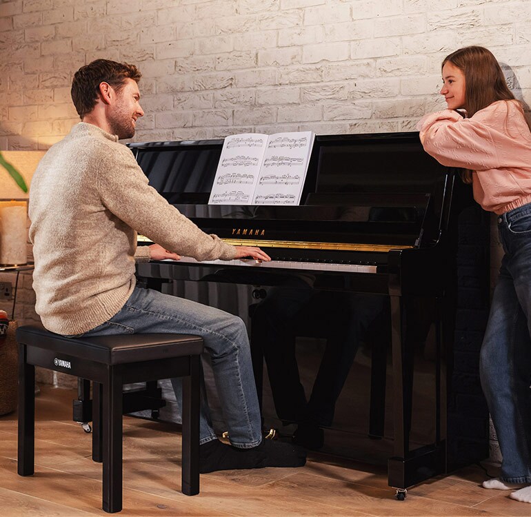 En mor og datter spiller med glede på det opprettstående pianoet i B-serien