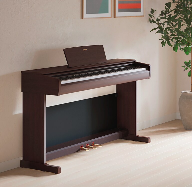 En stue med et ARIUS-piano, stueplanter og en sofa, harmonisk integrert i interiøret