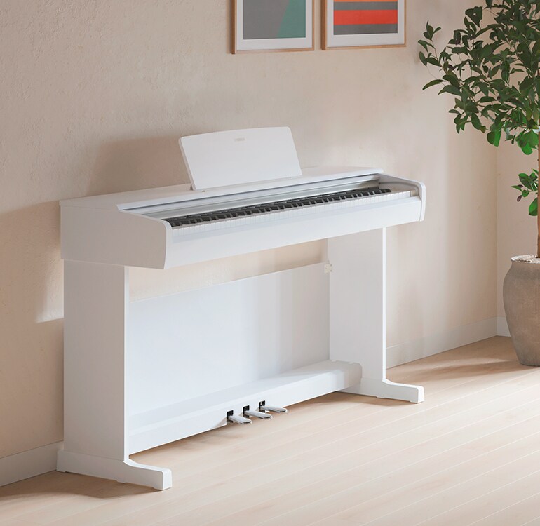 En stue med et hvitt ARIUS-piano, stueplanter og en sofa, harmonisk integrert i interiøret