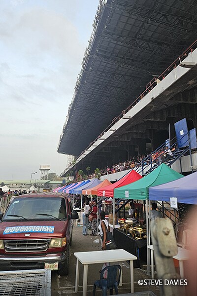 Grandstand seating and event operations area with tents and attendees at The Experience 2025 in Lagos, Nigeria.